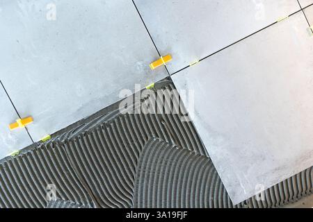 Verlegung von Keramikfliesen mit Fliesennivelliersystem und Zementkleber Stockfoto