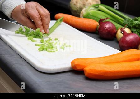 Frau zerkleinert Sellerie in kleine Würfel Stockfoto