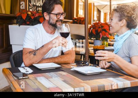 Erwachsenes glückliches Paar genießt gemeinsam das Mittagessen im Restaurant und toast Rotwein am Tisch. Reife Menschen Mann und Frau im Sommerurlaub Freizeit Essen und Trinken. Dateitag Stockfoto