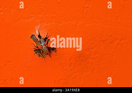 Lackschäden an einer orangefarbenen Metallwand Stockfoto