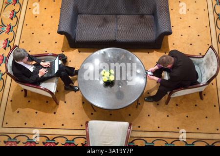 Geschäftsleute, die Laptops und Telefone in der Hotellobby nutzen Stockfoto