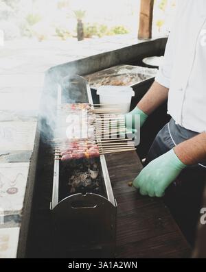 Mann Kochen der Straße essen viele Spieße mit Lamm Fleisch gekocht, gegrillt, namens arrosticini in Italien. Stockfoto