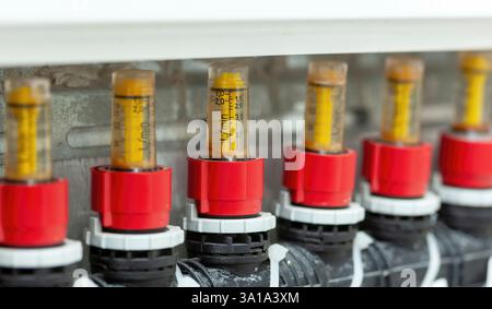 Regler des Durchflussmessers, Regler des Heizungs- und Kühlkrümmers. Gelbe Rotameter messen den Wasserdurchfluss in einem Heizsystem. Stockfoto