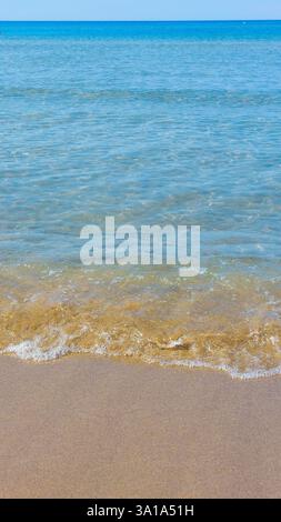 Sanfte Wellen von kristallklarem Wasser, die am Sandstrand eines Strandes plätschern Stockfoto