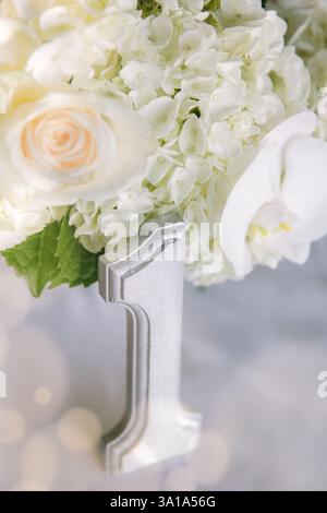 Eine wunderschöne Blumenausstellung mit weißen Hortensien und Rosen, gekennzeichnet mit einer silbernen Nummer 1 für einen besonderen Anlass. Stockfoto