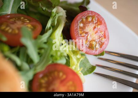 Frischer Salat mit Kirschtomaten und Gemüse auf einem weißen Teller, fertig zum Verzehr Stockfoto