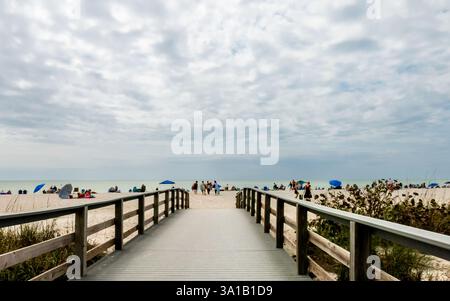 2/22/2025 Sanibel Island, FL, USA: Eine Holzbrücke mit Leitplanken führt die Strandbesucher zum Bowman's Beach auf Sanibel Island, FL. Ein dramatischer bewölkter Himmel Co Stockfoto