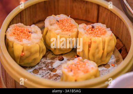 Goldene Garnelen und Schweinefleisch Shu Mai Dim Sum Knödel in einem San Francisco Restaurant mit chinesischer Küche, garniert mit Krabbenrogen, gedämpft in einem Bambuskorb Stockfoto