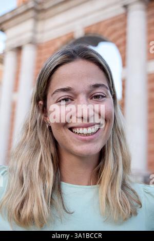 Eine junge Frau lächelt vor einem Backsteinbogen Stockfoto
