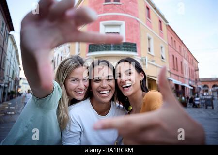 Drei glückliche Freundinnen, die Selfie mit Händen in einer Stadtstraße machen Stockfoto
