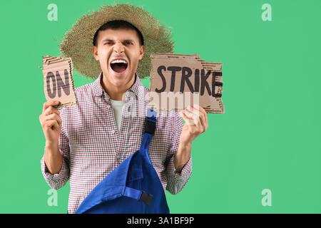 Protest gegen männlichen Landwirt, der ein Plakat mit STREIKTEXT vor grünem Hintergrund hält Stockfoto