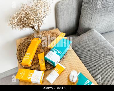 Sonnenpflegeprodukte auf einem Couchtisch in gemütlicher Wohnzimmeratmosphäre Stockfoto