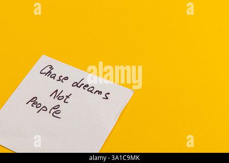 Eine handschriftliche Notiz inspiriert einzelne dazu, ihren Träumen Vorrang vor der Verfolgung anderer zu geben. Vor einem leuchtend gelben Hintergrund vermittelt die Botschaft Stockfoto