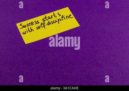 Ein hellgelber Haftnotiz mit der Botschaft Erfolg beginnt mit Selbstdisziplin auf einem leuchtend violetten Hintergrund ist ein inspirierender remi Stockfoto