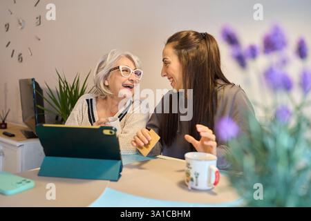 Seniorin und Tochter genießen Online-Shopping mit Tablet und Kreditkarte Stockfoto