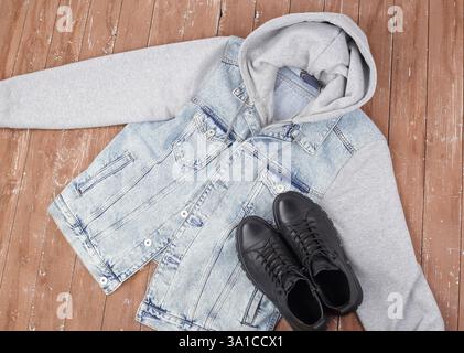 Kleidung, Schuhe und Accessoires - Top View Closeup Jeans Kapuzenjacke und Winterfellstiefel auf hölzernem Hintergrund Stockfoto
