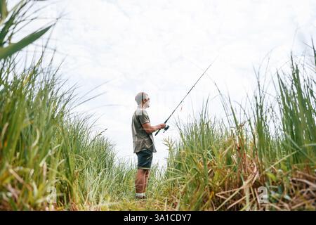 Ein hübscher Mann mit Sonnenbrille fischt draußen. Stockfoto