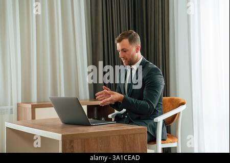 Im Büro mit Laptop. Ein hübscher Geschäftsmann ist drinnen im Hotelzimmer. Stockfoto
