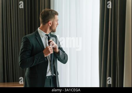 Vorstellung von Eleganz. In Anzug und Krawatte. Geschäftsmann ist drinnen im Hotelzimmer. Stockfoto