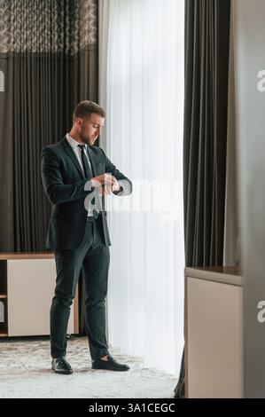 Vorstellung von Eleganz. In Anzug und Krawatte. Geschäftsmann ist drinnen im Hotelzimmer. Stockfoto