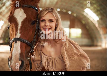 Porträt einer schönen jungen Frau, die mit Pferd drinnen ist. Stockfoto