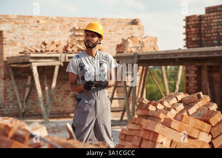 Tragen der Handschuhe. Ein hübscher Indianer ist auf der Baustelle. Stockfoto
