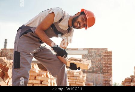Seitenansicht, Arbeiten und Platzieren der Steine. Ein hübscher Indianer ist auf der Baustelle. Stockfoto