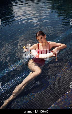 Eine junge Frau in rotem Badeanzug ist im Pool. Stockfoto