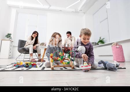 Hyperaktive Kinder, die spielen und ihre überforderten Eltern zu Hause, Tiefwinkelblick Stockfoto