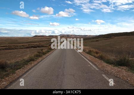 Eine gerade Straße in den Bardenas Reales unter einem blauen Oktoberhimmel (Spanisch Navarra) Stockfoto