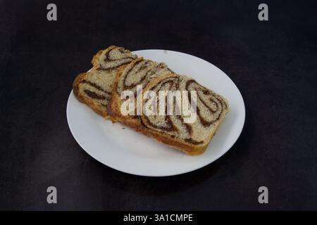 Drei Brotscheiben mit Schokoladenkugeln auf einem weißen Teller. Die Platte befindet sich auf einer dunklen Oberfläche Stockfoto