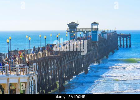 Oceanside, Kalifornien - 27. Dezember 2024: Oceanside Pier voller Besucher, gesäumt von Lichtern vor dem Hintergrund des Ozeans. Stockfoto
