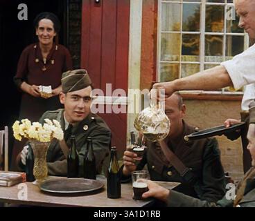 American Airmen trinken vor einem öffentlichen Haus in England und werden von der Vermieterin und Vermieterin bedient, 1943–1944. Aus „Time to Remember – Round the Clock“, 1943–1944 (Rolle 1); Dokumentarfilm über Ereignisse von 1943–1944, hauptsächlich Bombardierungen über Europa. (Farbige Schwarz-weiß-Standbilder) Stockfoto
