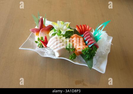 Ein Teller Sushi mit einer Vielzahl verschiedener Fisch- und Gemüsesorten. Die Präsentation ist sehr künstlerisch und optisch ansprechend Stockfoto