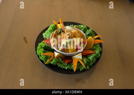 Ein Teller mit einem grünen Salat drauf. Der Salat besteht aus verschiedenen Gemüsesorten wie Karotten, Tomaten und Gurken. Die Platte wird platziert Stockfoto