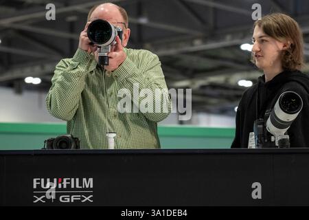 London, Großbritannien. 8. März 2025. Am Eröffnungstag von The Photography & Video im Excel London probieren Besucher lange Objektive auf dem Fuji Stand aus. Die Veranstaltung richtet sich an Profis und Amateure, die die neuesten Techniken erlernen, von Branchenführern und Experten hören und die neueste Technologie und Ausrüstung ausprobieren können. Die Show findet vom 8. Bis 11. März statt. Quelle: Stephen Chung / Alamy Live News Stockfoto