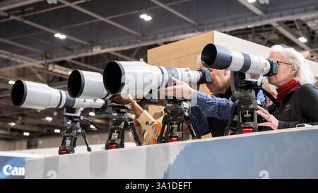 London, Großbritannien. 8. März 2025. Am Eröffnungstag von The Photography & Video im Excel London probieren Besucher lange Objektive auf dem Canon Stand aus. Die Veranstaltung richtet sich an Profis und Amateure, die die neuesten Techniken erlernen, von Branchenführern und Experten hören und die neueste Technologie und Ausrüstung ausprobieren können. Die Show findet vom 8. Bis 11. März statt. Quelle: Stephen Chung / Alamy Live News Stockfoto