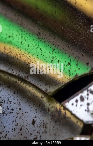 Veralteter Spiegel mit Rissen und beschädigten Stellen, an denen die reflektierende Rückseite verschwunden ist, verzerrt Formen in Grün- und Gelbtönen Stockfoto