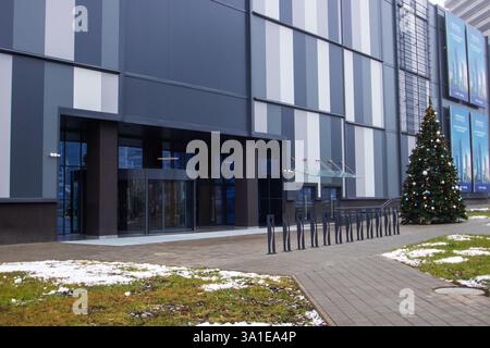 Weißrussland, Minsk - 26, 12, 2024: Vor einem großen Geschäftsgebäude befindet sich ein außergewöhnlich großer und wunderschön geschmückter Weihnachtsbaum Stockfoto