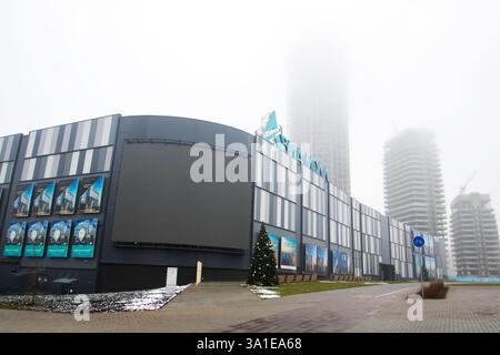 Weißrussland, Minsk - 26, 12, 2024: Ein großes und beeindruckendes Geschäftsgebäude mit einem wunderschönen Weihnachtsbaum direkt vor dem Eingang Stockfoto