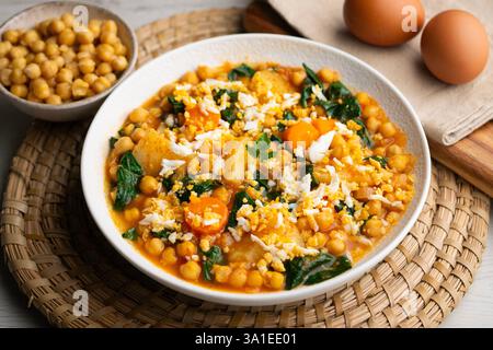 Köstlicher Eintopf aus Kartoffeln und Kichererbsen, gedünstet mit Spinat, Gemüse und gekochtem Ei. Traditionelles spanisches Rezept. Stockfoto