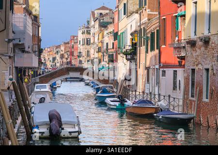 Venedig, Italien - 12. Oktober 2024: Ein schmaler Kanal, gesäumt von bunten historischen Gebäuden und kleinen Booten, die entlang des Wassers vertäut sind Stockfoto