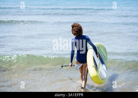 Unerkennbare Surferin mit Paddleboard im Meer Stockfoto