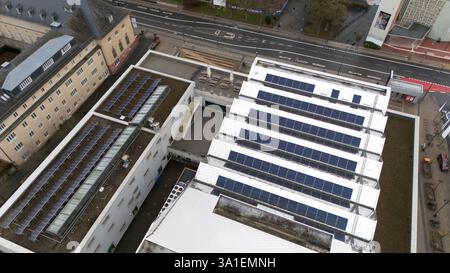 Hochwinkelansicht mehrerer Gebäude mit Solarpaneelen auf ihren Dächern, die Lösungen für erneuerbare Energien und eine nachhaltige städtische Infrastruktur hervorheben. Stockfoto