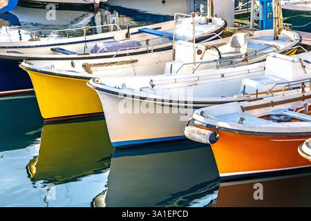 Kleine Fischerboote, die in ruhigen Hafengewässern ankern und ihre leuchtenden Farben widerspiegeln. Stockfoto