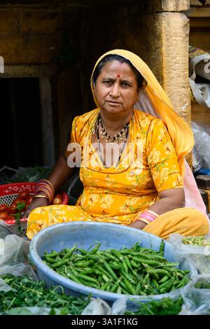 Jaisalmer, Rajasthan, Indien - 12. Februar 2025: Frau im traditionellen gelben Kleid verkauft Gemüse. Stockfoto