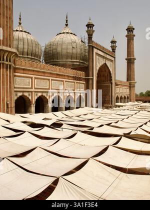 Leinwandtöne bedecken den Innenhof von Jama Masjid, Neu-Delhi, und bieten Schutz vor der Sonne unter den großen Mogulkuppeln und Minaretten. Stockfoto