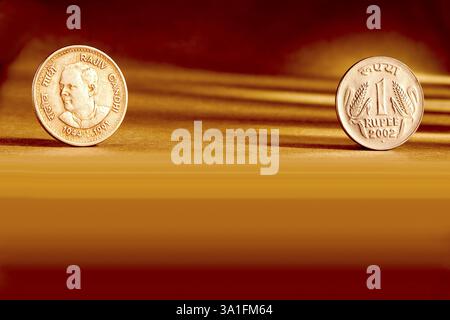 Doppeltes Paar indische Währung eine Rupie Münze Vorder- und Rückseite Weise geprägt Rajiv Gandhi 1944-1991 auf orangem Hintergrund Stockfoto