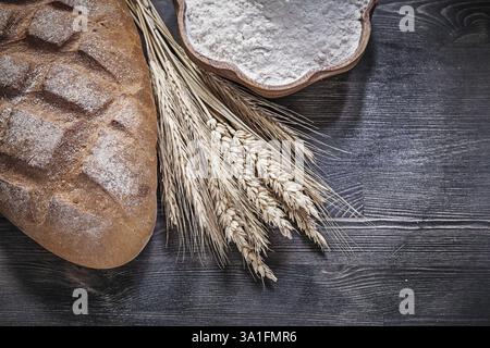 Brotbrot, Weizen, Roggenohren, Holzschale mit Mehl auf Holzbrett Stockfoto