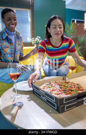 Eine Gruppe von Freunden genießt köstliche Pizza gemeinsam im Komfort ihres Zuhauses Stockfoto